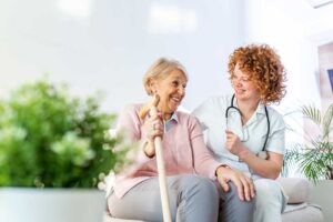 Older adult choosing clothing while a caregiver offers respectful assistance in a bright private room